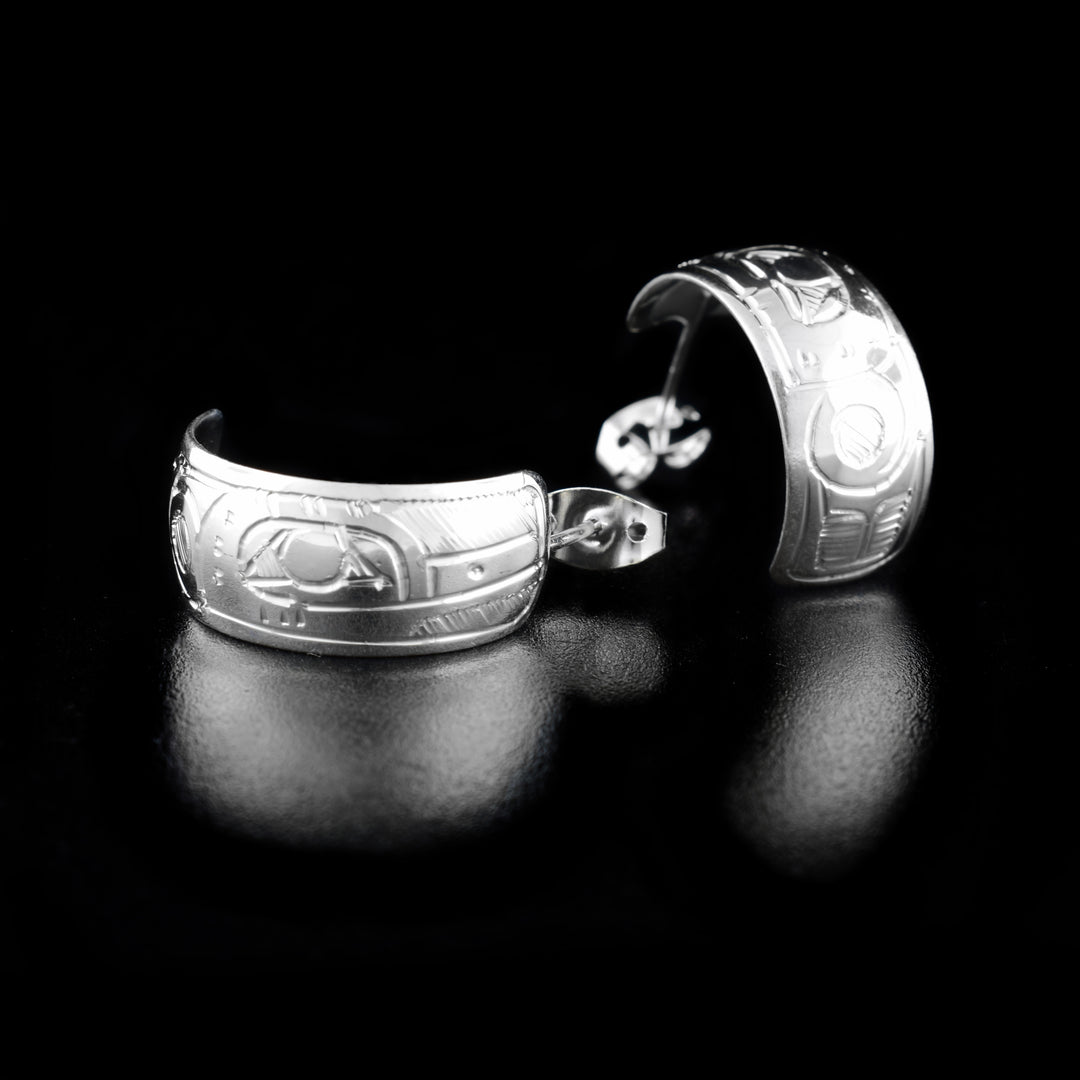 These Hummingbird earrings are made from sterling silver and have a wide band curved into a hoop with a gap in the back. There are depictions of the Hummingbird carved into the surface of the bands.