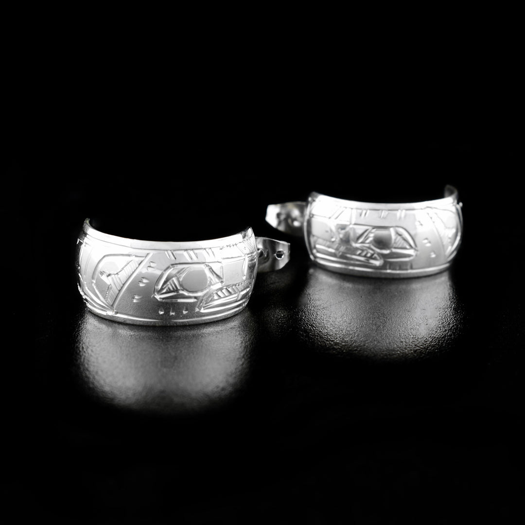 These Eagle earrings are made from sterling silver and they have thick bands that wrap into hoops. There are depictions of the Eagle carved into the surface of the hoops.