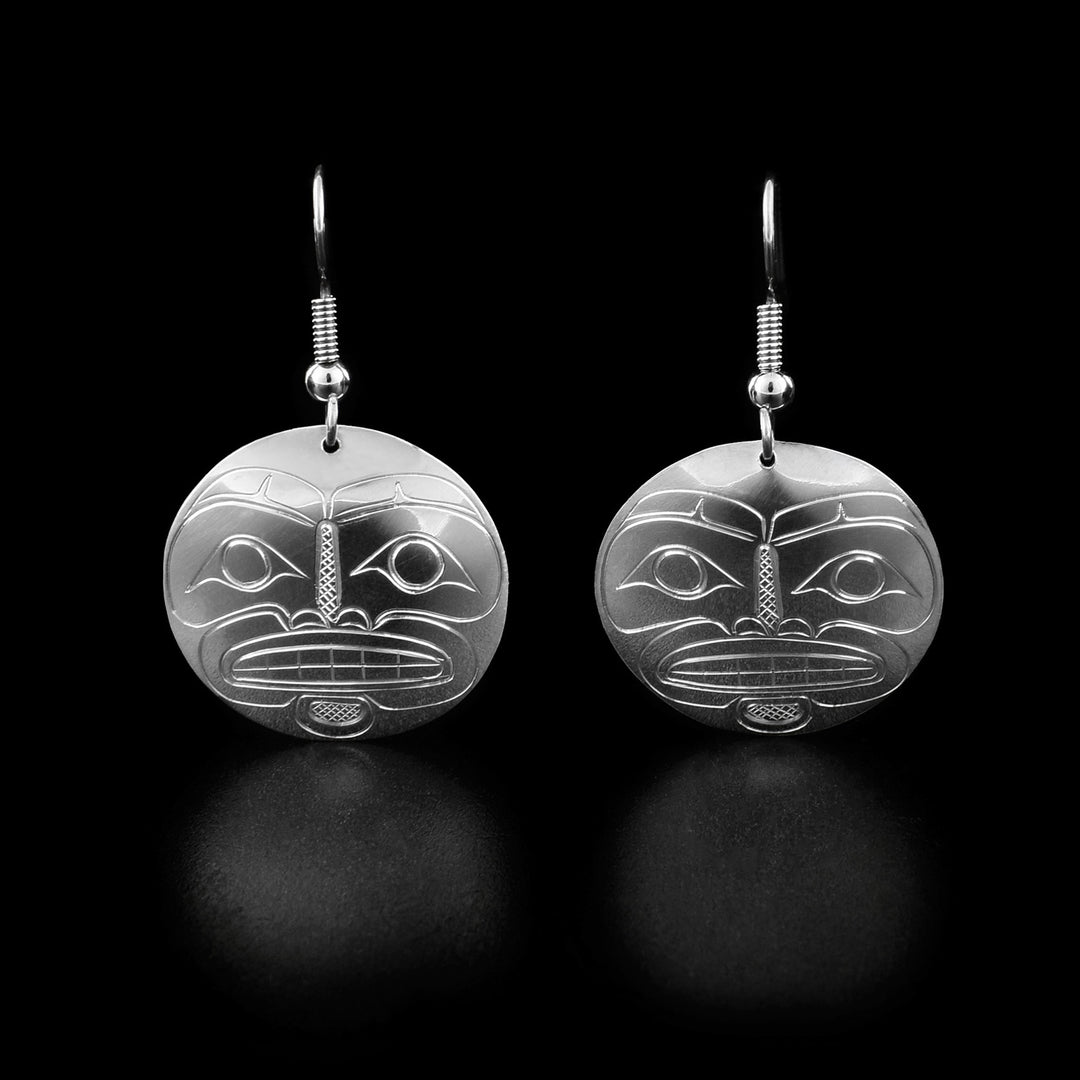 These moon dangle earrings are round in shape and have the full face of a moon with large eyes, a nose, and teeth looking forward.