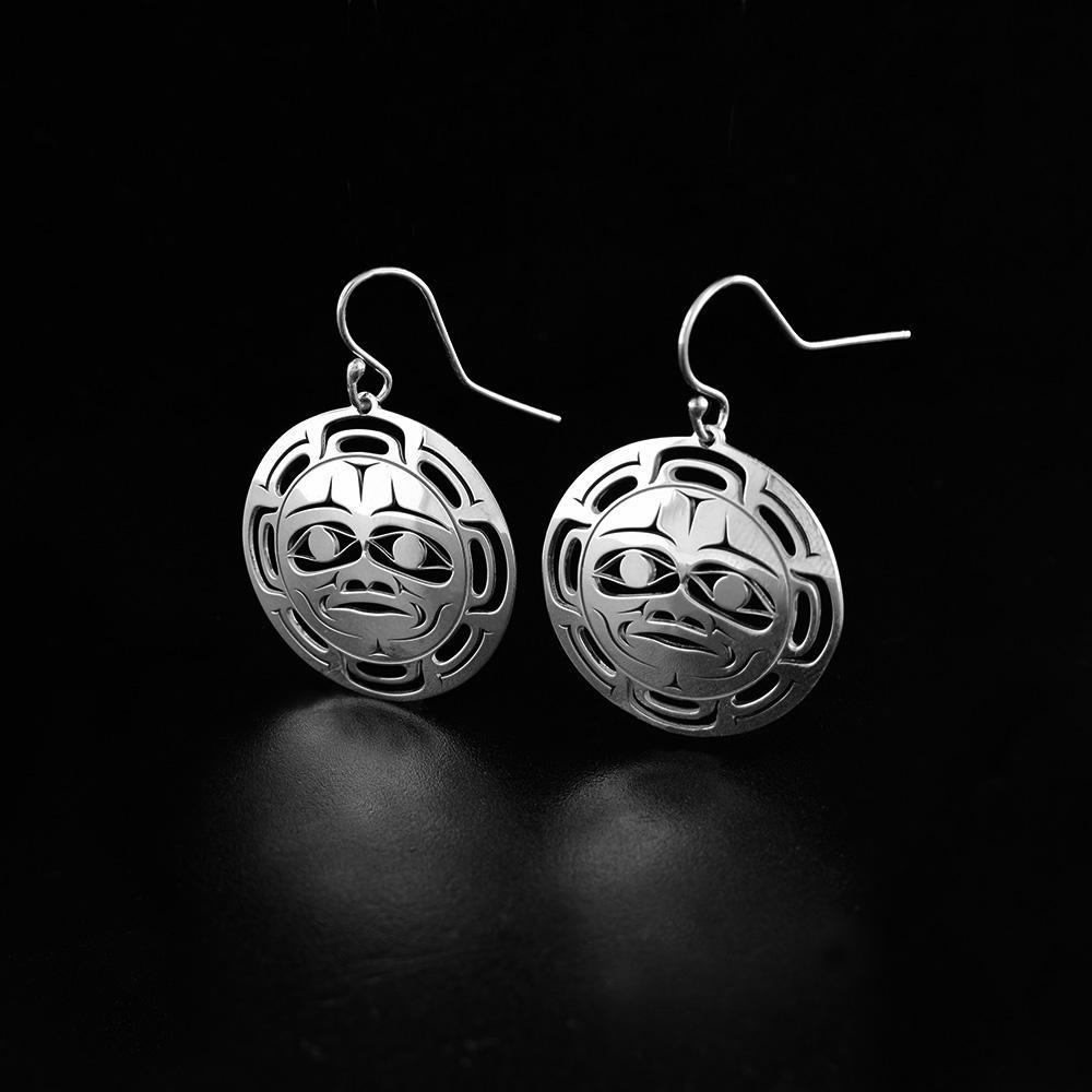These dangling Moon earrings are made from sterling silver and have circle shaped hangs. There are cutout designs on the hangs that depict the Moon.