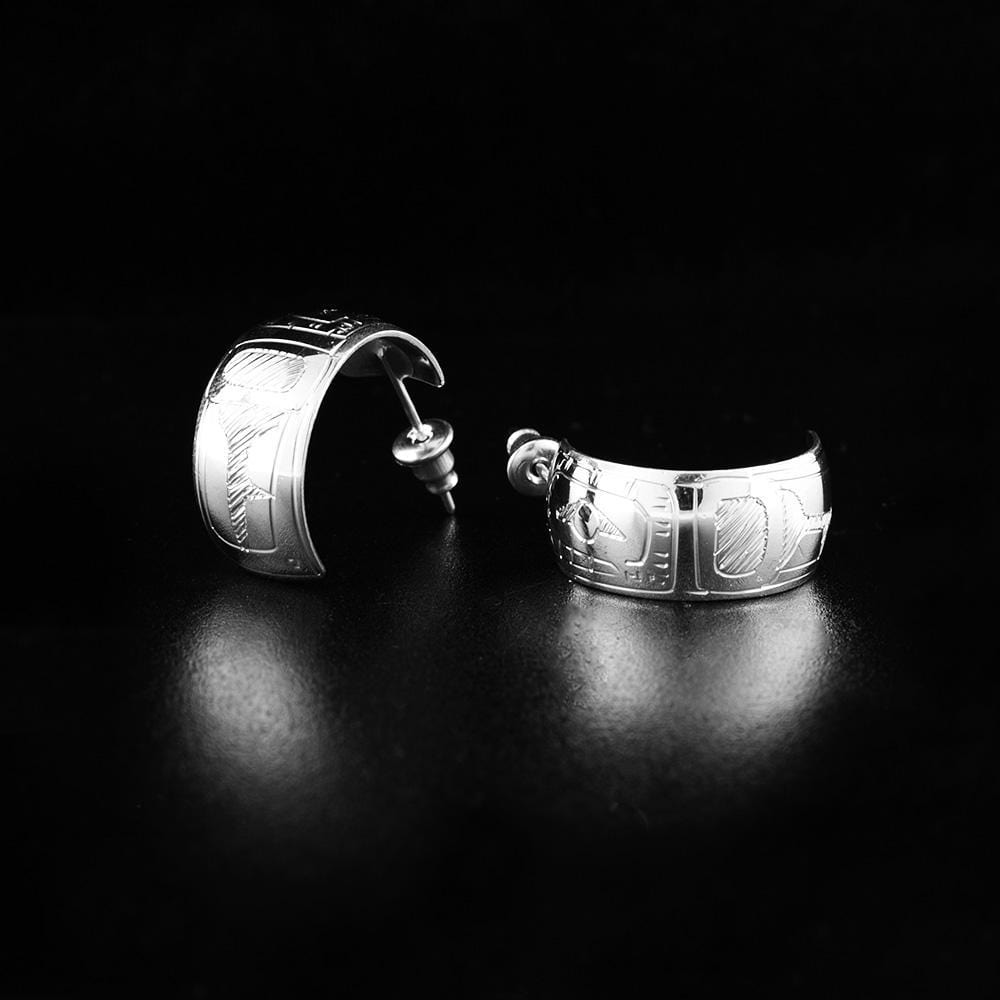 These Orca, wide hoop earrings are made from sterling silver and have a single hoop, band with a gap in the back. There are depictions of the Orca carved into the surface of the hoops.