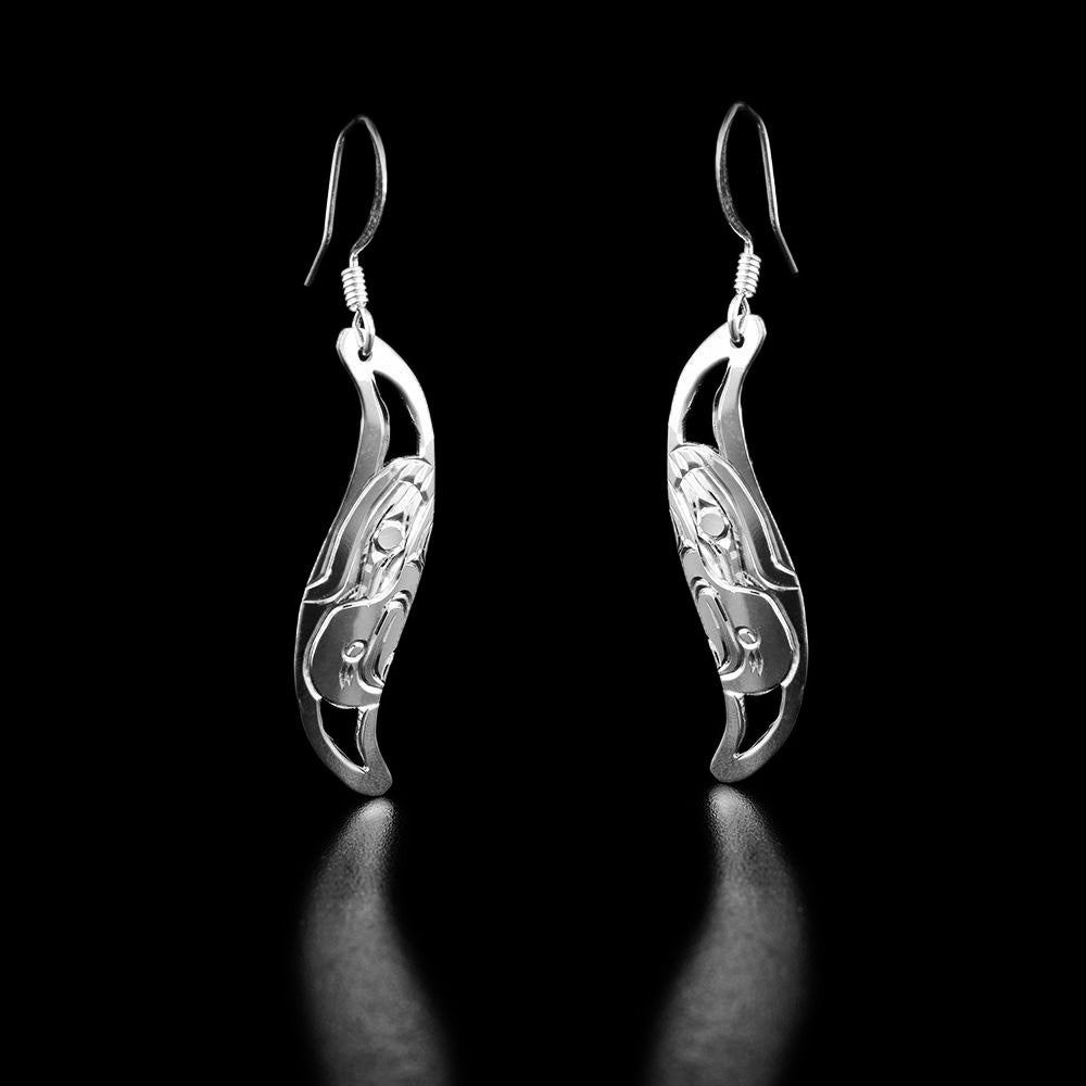Sterling Silver Leaf Style Eagle Earrings by Harold Alfred. Each earring is in the shape of a leaf. The artist has hand-carved the profile of an eagle's head facing downwards in the center of each earring. The eagle has a short, large beak pointing downward. It also has a feather on the top of its head. The background is cut out.
