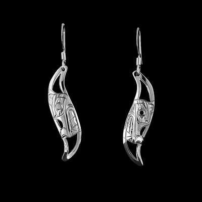 Sterling Silver Leaf Style Wolf Earrings by Harold Alfred. Each earring is in the shape of a leaf. On the inside of each earring the artist has hand-carved the profile of a wolf's head facing inward. The wolf a long, narrow snout that points up at the end. In addition, the wolf has a small ear and an open mouth that shows its teeth. The background has been cut out.