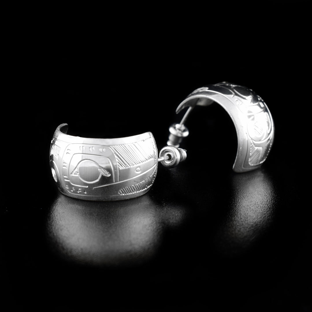 These Hummingbird earrings are made from sterling silver and have a single, wide band curved into a hop with a gap in the back. There are depictions of the Hummingbird carved into the band.