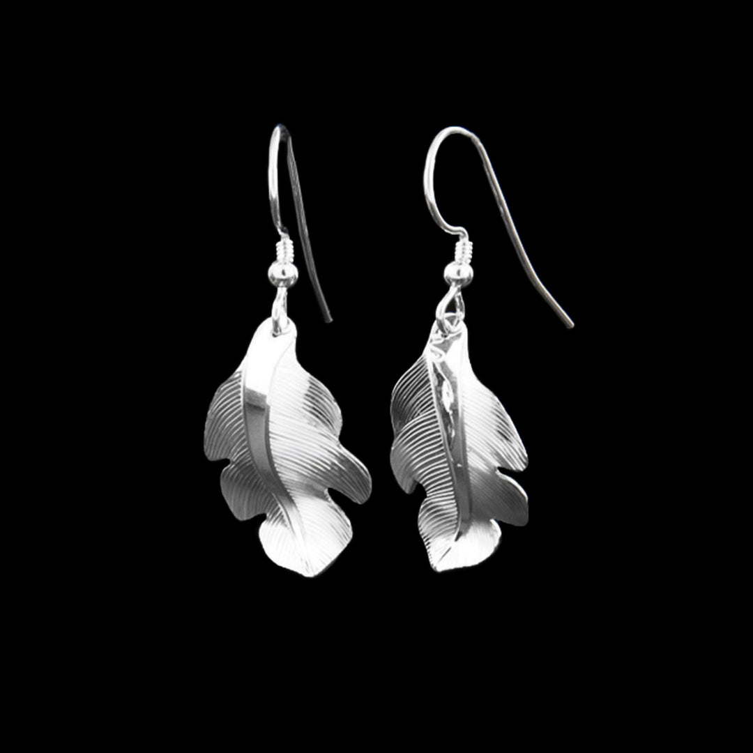 Sterling Silver Owl Feather Dangle Earrings by Fred Myra. Each earring is in the shape of a feather. The artist has hand-carved intricate designs along the earring to represent the delicate, wispy texture of a feather.