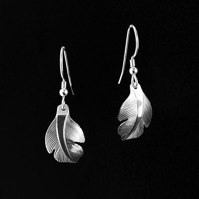 Sterling Silver Small Owl Feather Earrings by Fred Myra. Each earring is in the shape of a feather. The artist has hand-carved intricate designs along the earring to represent the delicate, wispy texture of a feather.