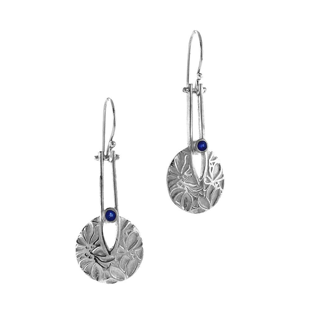 These sapphire drop earrings are made from sterling silver and sapphire gemstones and have circle hangs at the bottom of them. The hangs have a textured flower pattern on it with sapphires set into a small cutout in the hangs.
