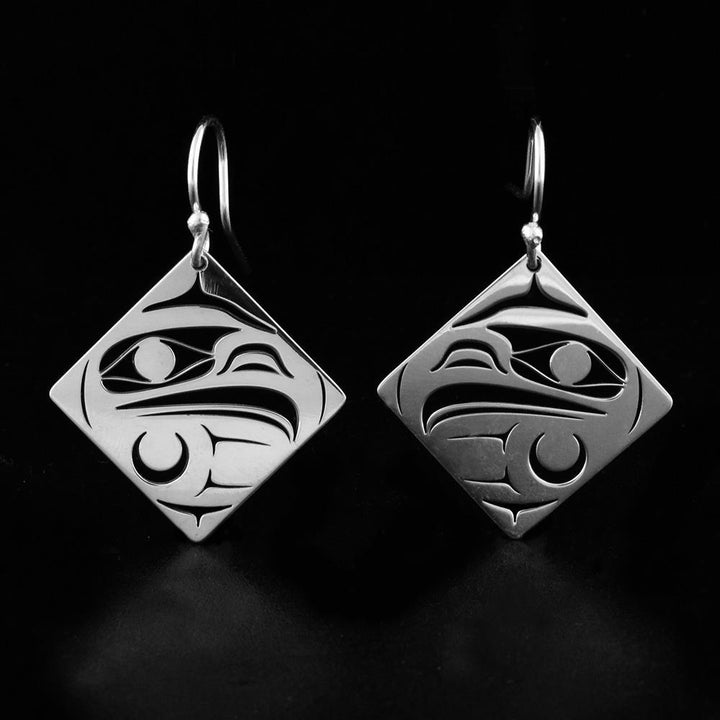 These dangling, diamond shaped earrings are made from sterling silver and have cutout designs on the hangs that depict the Eagle.