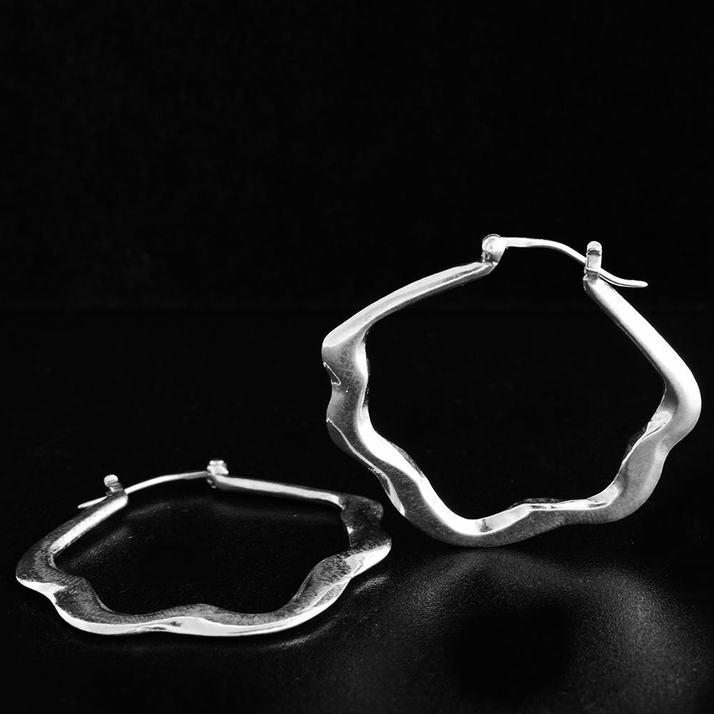 These large hoop earrings are made from sterling silver and have a wavy shape running along the hoops. The shape of the hoops resemble a flower blossom.