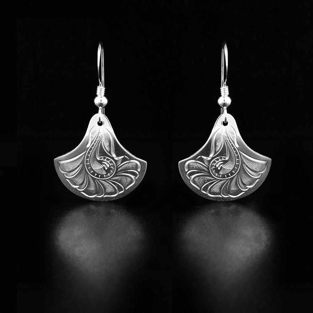 These flower dangle earrings are made from sterling silver and have hangs that are shaped like flowers. There are carvings on the surface of the hangs depicting floral designs.