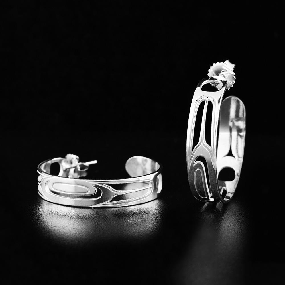 These sterling silver feather earrings are made from a single, thin band coiled into a hoop with a gap in the back. There are cutout designs on the hoops depicting feathers.