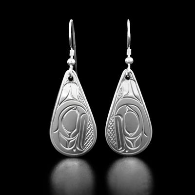 Sterling Silver Teardrop Raven Earrings by Victoria Harper. The design depicts the profile of a raven's head with a short beak looking towards the ground with a small feather attached to the back of the head. The background has been neatly hand-carved in a crisscross pattern to allow for the raven to stand out.