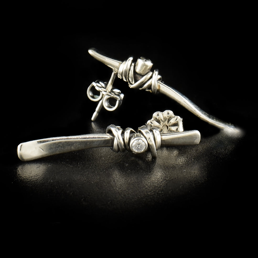 These cubic zirconia drop earrings have long, twig shape drops made from sterling silver with the gems imbedded into the center of them. There are sterling silver wrappings around the cubic zirconia gems.