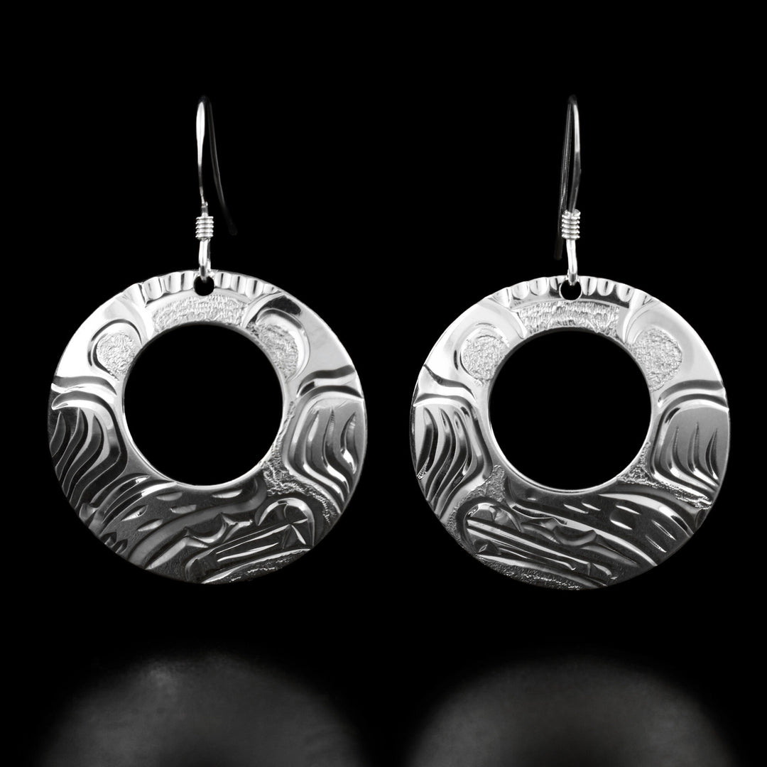 These bear earrings are circular in shape and have a small cut-out hole in the top center. Each earring has the profile of a bear's head and its paws on both sides.
