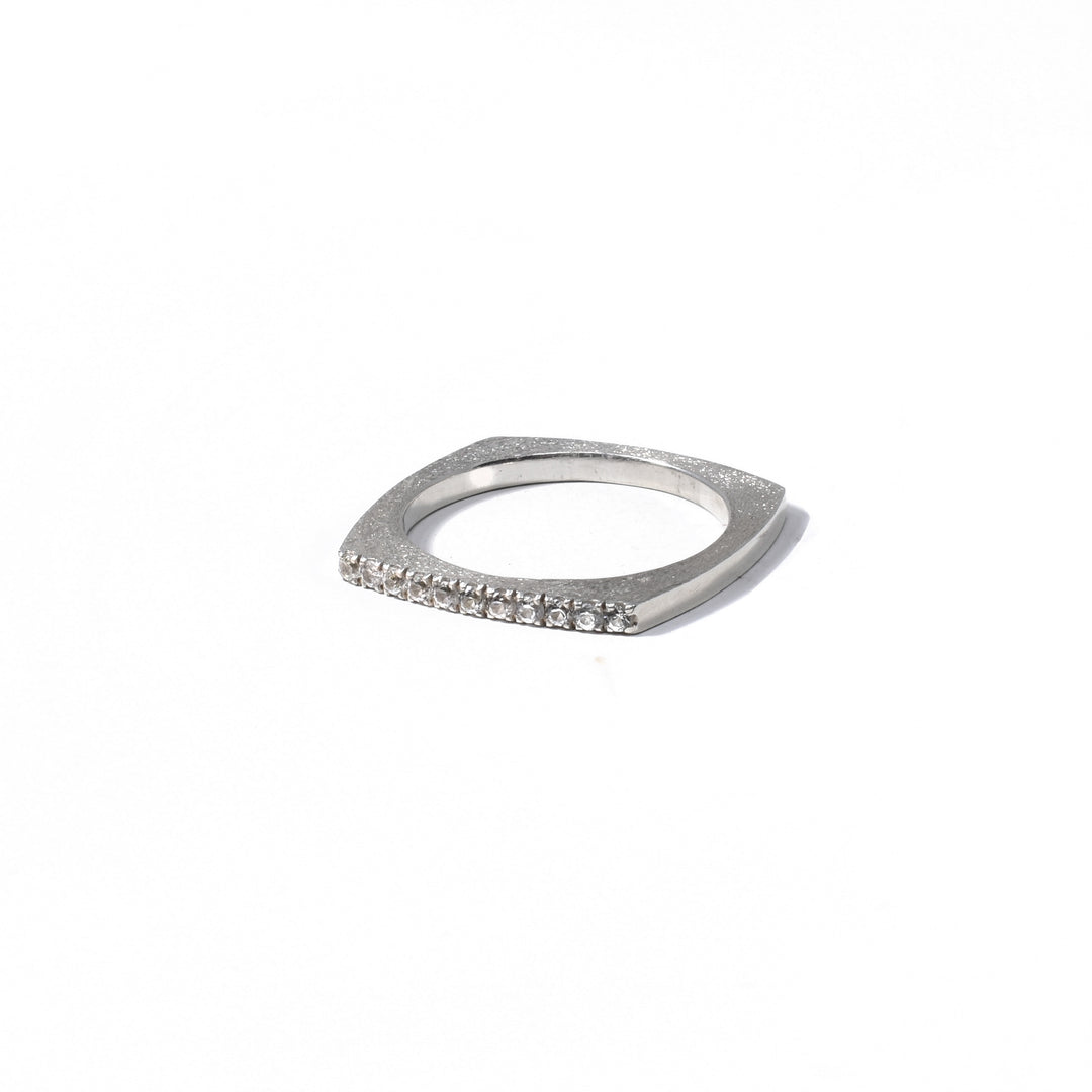 This sterling silver sapphire ring has a thick, but thin band and is square shaped. There is a dimpled texture on the surface of the band and on end of the ring is lined with white sapphires.