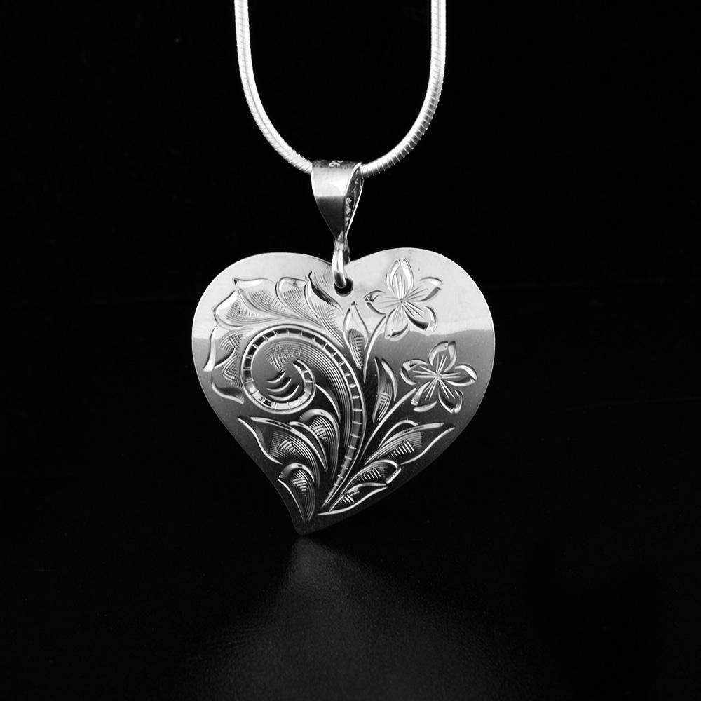 This sterling silver heart pendant necklace has intricate carvings on the surface of it depicting flowers.