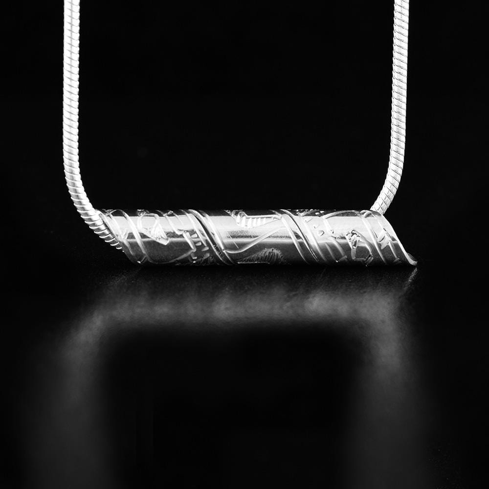 This spiral pendant is made from sterling silver and has a band that has been coiled into a tube. There are carvings on the surface of the band that depict the Orca.