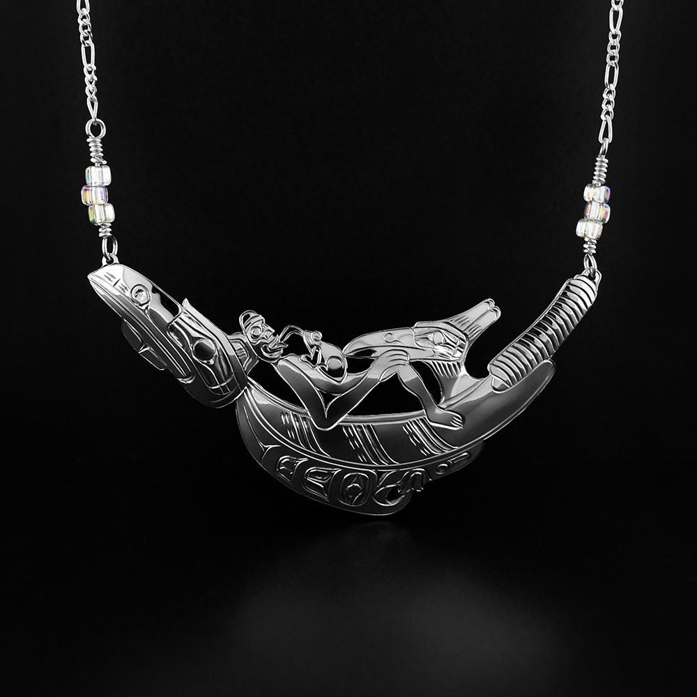 This sterling silver necklace depicts a Raven rattle that is traditionally given to the Chief's eldest son during a potlache. The piece depicts  a man laying on a large Raven rattle among the Thunderbird and the Frog legends. 