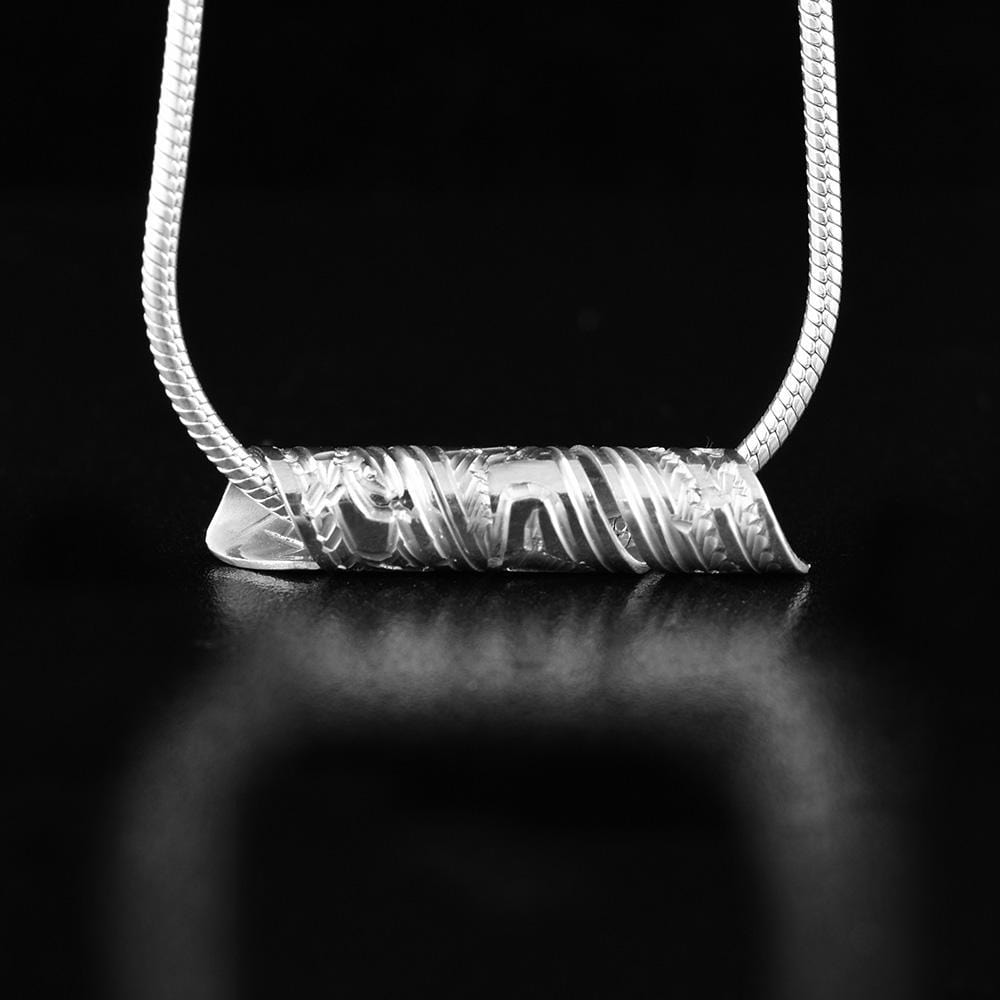 This spiral pendant is made from sterling silver and is made from a band that has been coiled into a tube. There are carvings on the surface of the band that depict the Eagle.