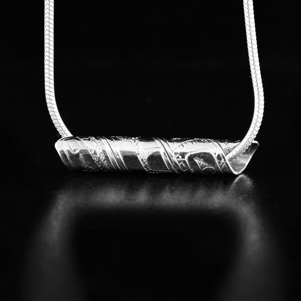 This sterling silver spiral pendant is made from a band that has been coiled into a tube. There are carvings on the surface of the band that depict the Raven.