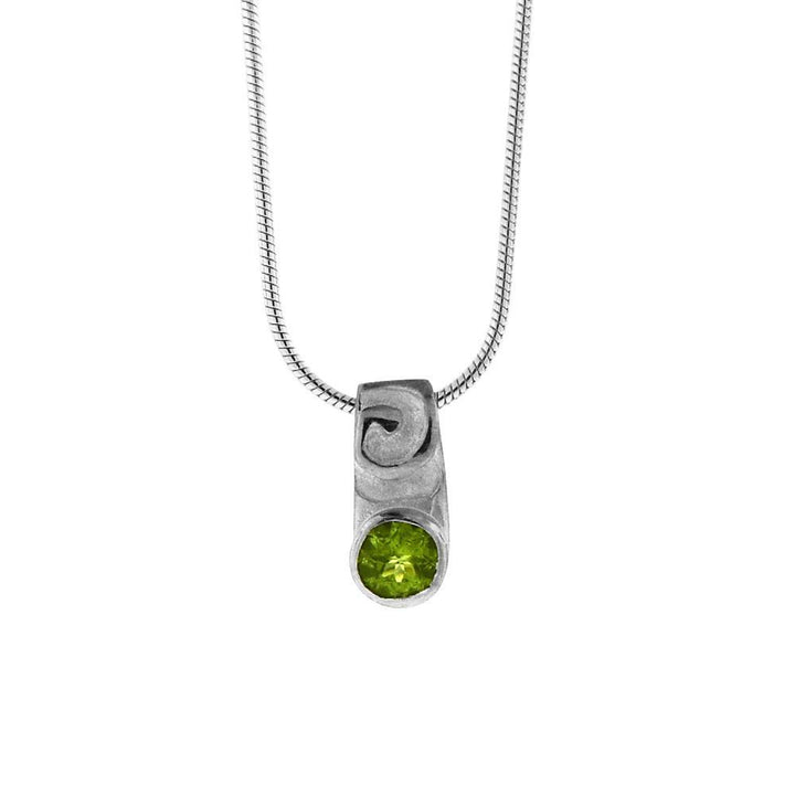 This peridot pendant necklace is made from sterling silver and peridot gemstone. There is a swirly design above the gemstone which is faceted in the bottom of the pendant.