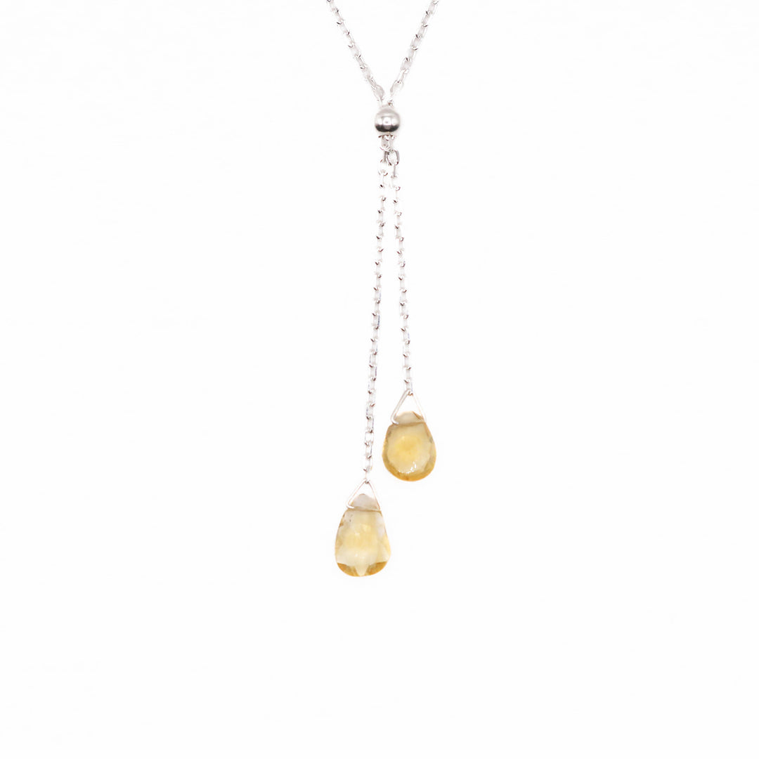 This gemstone lariat necklace is made from sterling silver and citrine gemstones. The citrine gems are teardrop shaped and hang from two lariats.