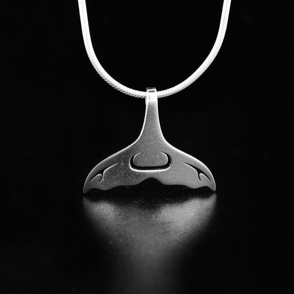 This whale tail pendant in the shape of a whale tail's with cut out accents in the center and on the side.