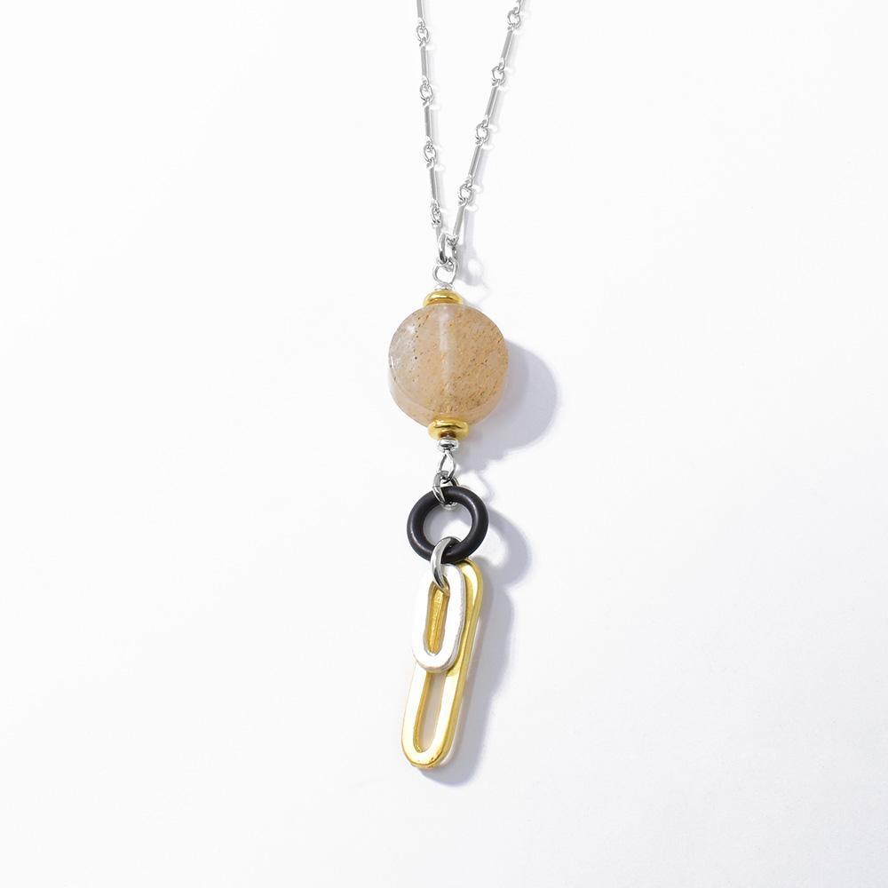 This dangling quartz necklace is made from strawberry quartz, gold vermeil, sterling silver and silicone. There is a thick, quartz circle with gold and silver loops hanging from a silicone ring under the gem.