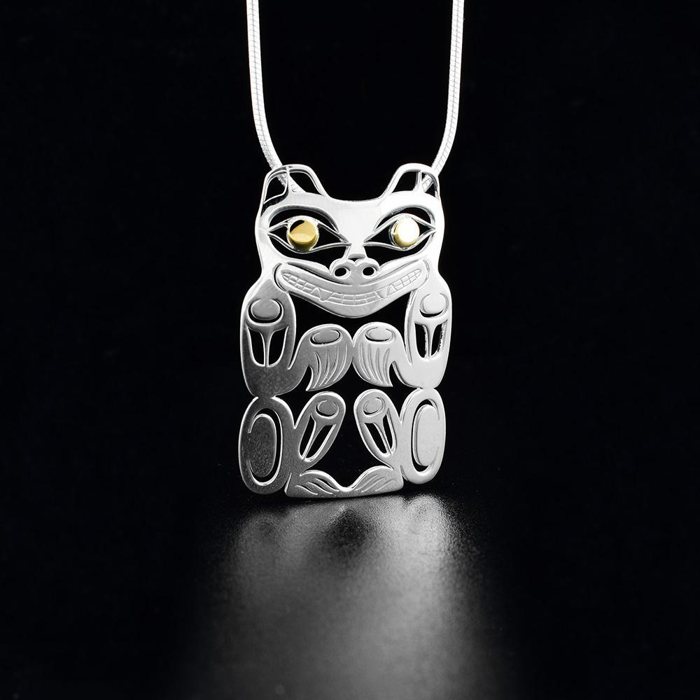 This cutout Bear pendant is made from sterling silver and 18k gold and is shaped like the Bear. There are cutout designs on the surface of it that depict the Bear and the eyes of it are made from gold.