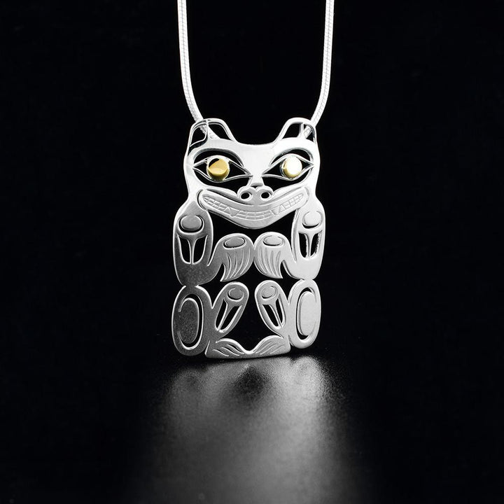 This cutout Bear pendant is made from sterling silver and 18k gold and is shaped like the Bear. There are cutout designs on the surface of it that depict the Bear and the eyes of it are made from gold.