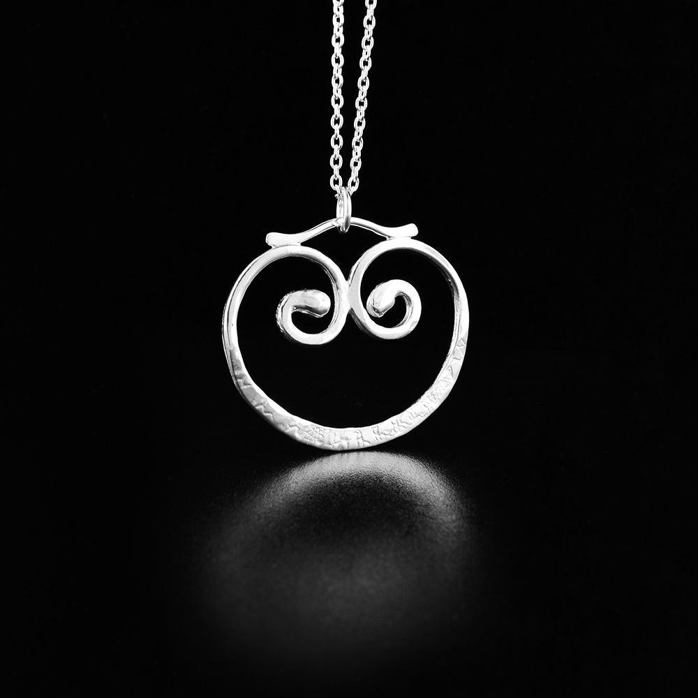 This dainty silver necklace is made from sterling silver and has a round pendant made from silver wire. The wires are curved and spiraled into interesting designs.