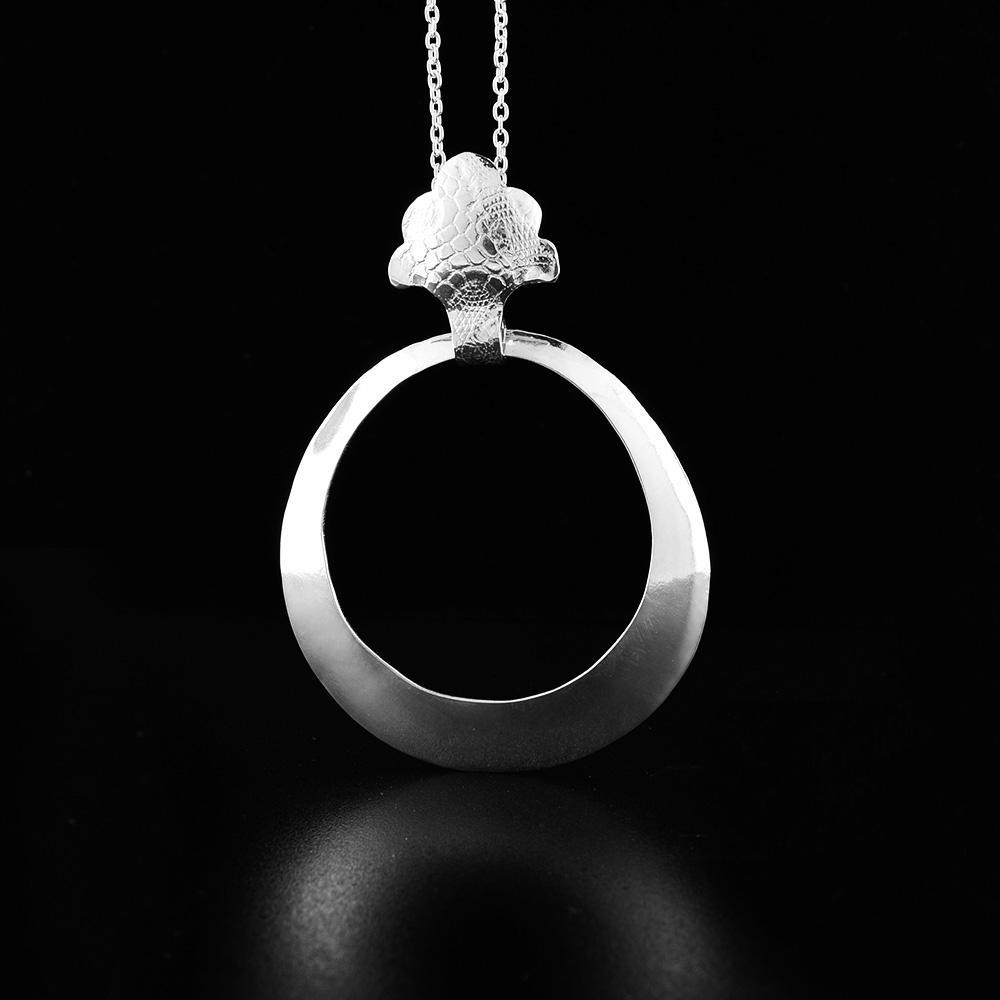 This sterling silver, hollow pendant is a large, tapered hoop attached to a decorative bail. There is a snake skin textured pattern on the surface of the bail.