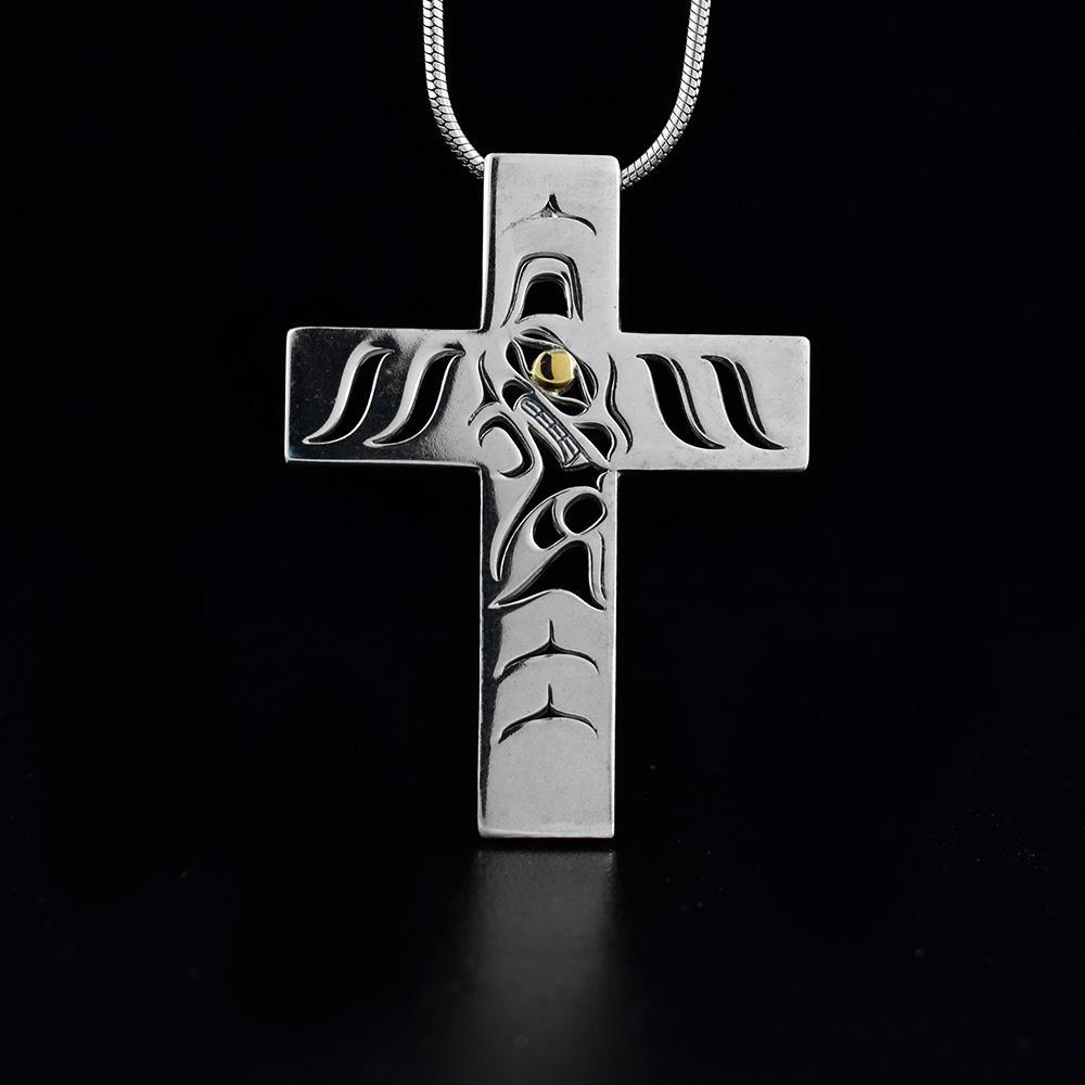 This sterling silver abd 18K gold cross pendant is large and cross shaped with cutout designs on the surface of it. These cutouts depict the Wolf and the eyes of it are made from the gold.