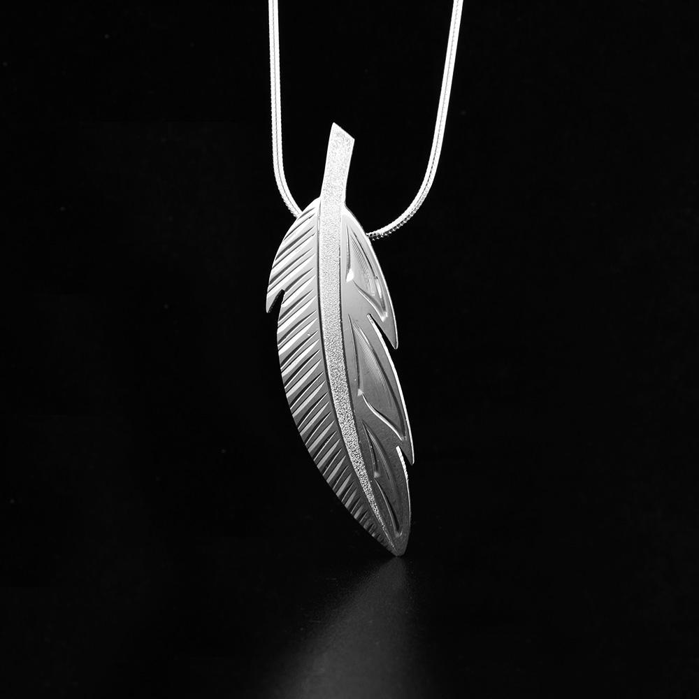 This feather pendant is made from sterling silver and is shaped like a feather. There are also carvings on the surface of the pendant that depict a feather.