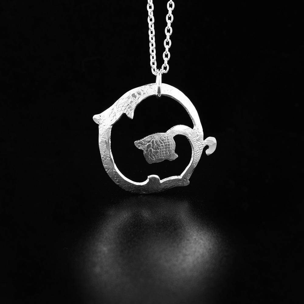 This sterling silver flower pendant features a thin flower that has been curved into a circular, cutout pendant. There are textures embossed onto the surface of the pendant using lace.