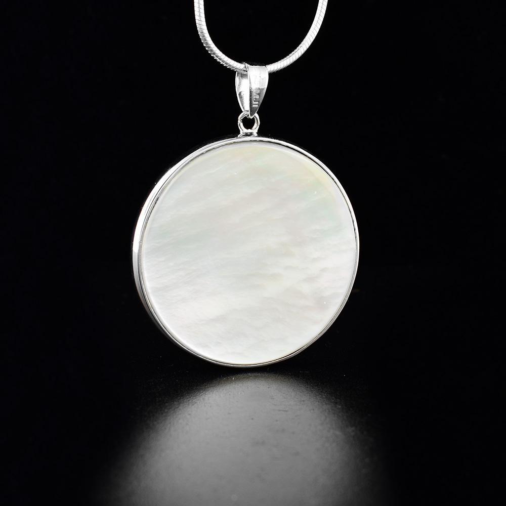 This abalone and mother of pearl pendant is made from sterling silver and has a dangling circle pendant. The pendant is double sided and has an abalone surface on one side and a mother of pearl surface on the other.