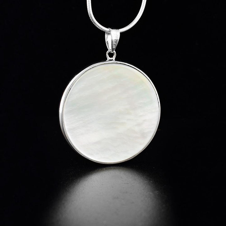 This abalone and mother of pearl pendant is made from sterling silver and has a dangling circle pendant. The pendant is double sided and has an abalone surface on one side and a mother of pearl surface on the other.