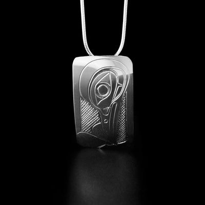 Sterling Silver Rectangular Hummingbird Pendant by Don Lancaster. The pendant is in a rectangular shape and the design depicts the profile of a hummingbird's head facing downwards. The hummingbird has a long, narrow beak and is drinking from a flower that the artist has hand-carved at the bottom of the pendant. The "background" of the pendant has been neatly hand-carved into a crisscross pattern to allow for the legend to stand out.