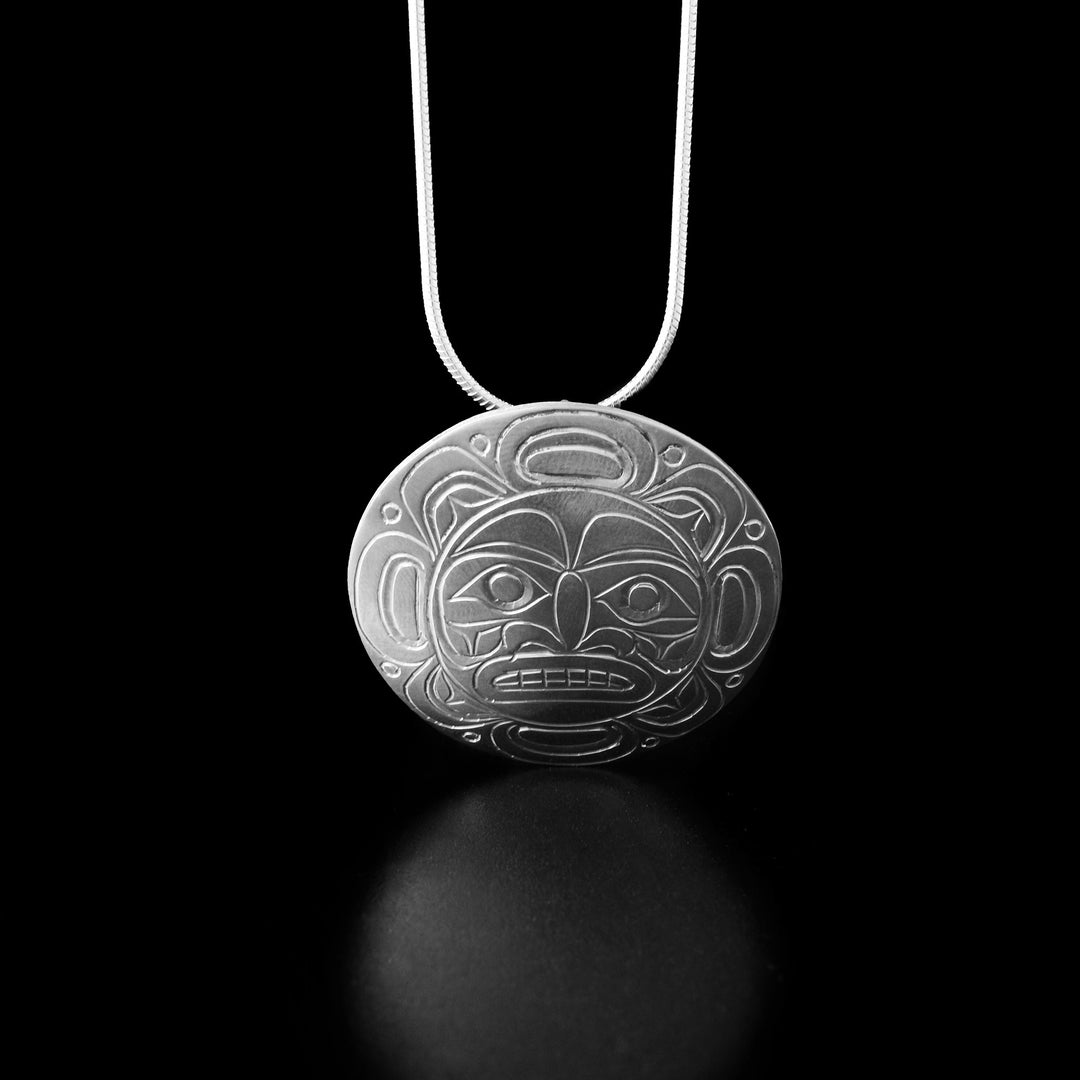 The design depicts the face of the moon in the center of the pendant looking straight ahead. Around the face of the moon the artist has carved intricate designs representing the moon's craters.