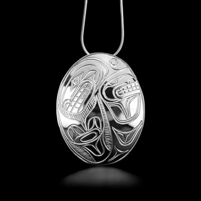 Sterling Silver Oval Orca Pendant by Paddy Seaweed. The design depicts the profile of a full bodied orca. The head of the orca is looking to the left with its mouth open. To the right of the head is the beginning of the body with the tail curving upwards at the end into a beautiful U-shape. The artist has neatly hand carved intricate details along the body of the orca.