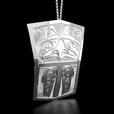The top part of this shield pendant is carved into the face of a thunderbird looking straight ahead. The bottom part has two raven heads facing downward.