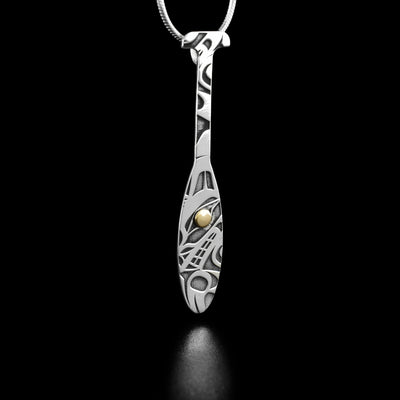 Sterling Silver and 18K Gold Wolf Paddle Pendant by Grant Pauls. The design depicts the profile of a wolf's head facing the left with a paw underneath. There are intricate designs that have been created along the pendant.