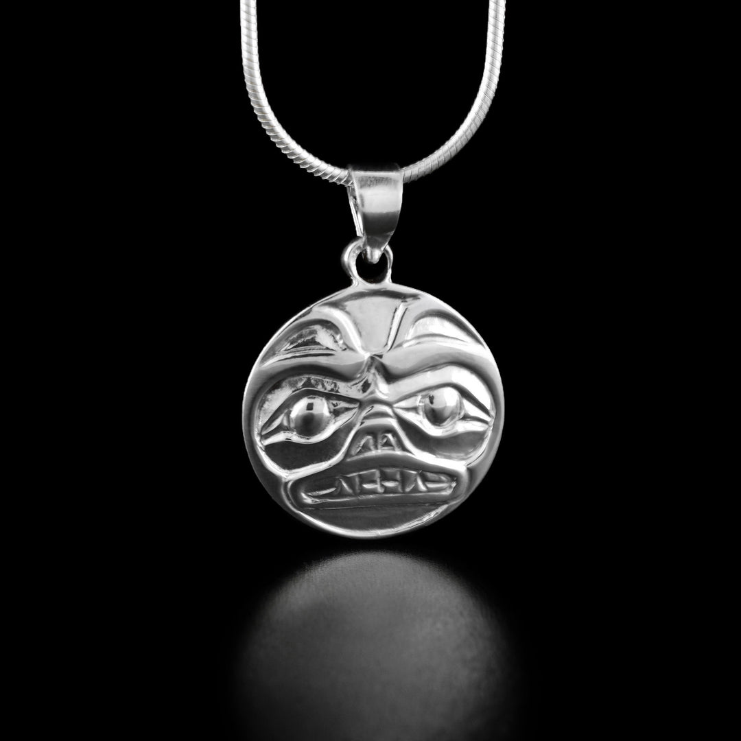 Sterling Silver Bear Cast Pendant by Carrie Matilpi. The design of the pendant is a bear looking forward. The bear has two small, pointy ears at the top; two large eyes staring forward; a short, stubby nose in the center of the pendant; and a set of pointy teeth underneath the nose.