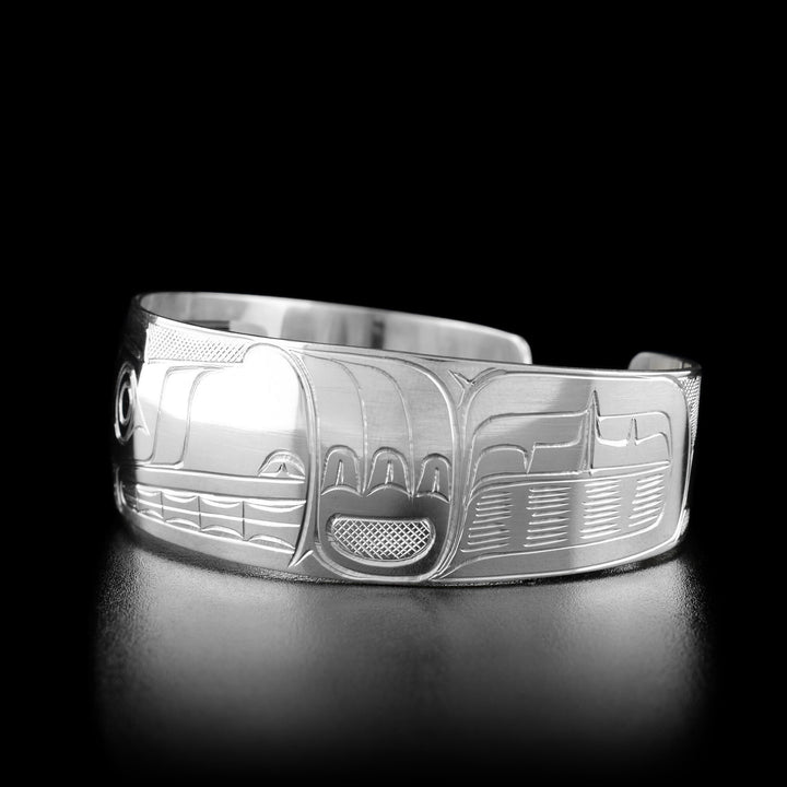 Right angle photo of the bracelet shows carved designs representing the fur of the wolf and its large paw mid-air.