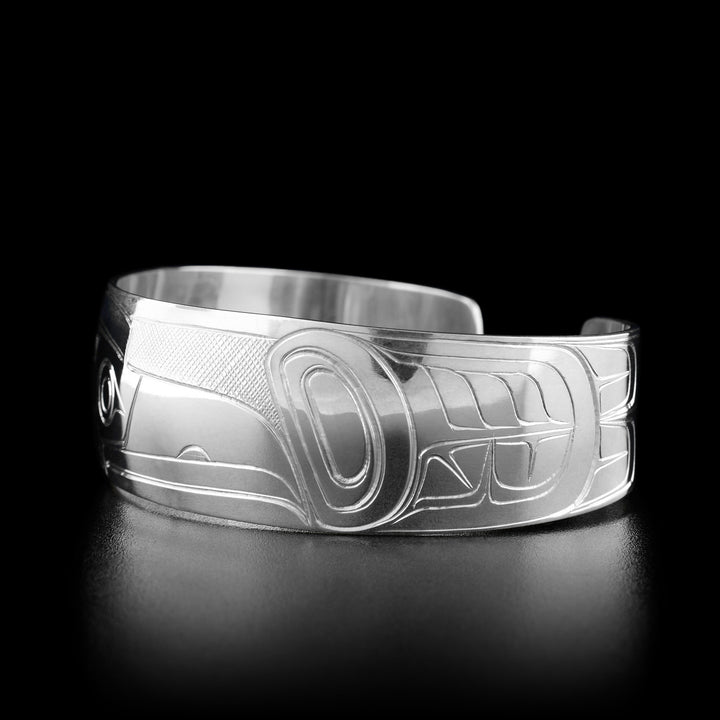 Right angle photo of the bracelet shows carved designs representing the body of the raven and its feathers.
