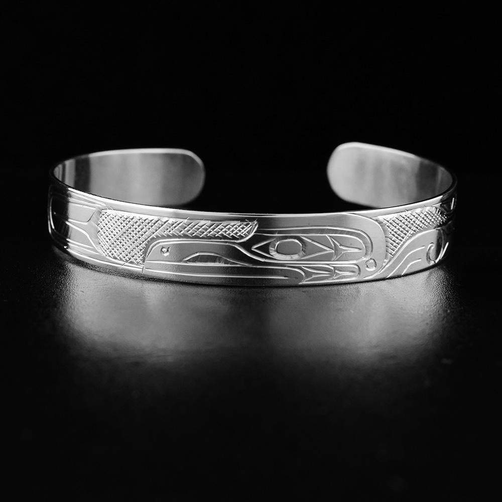 This Raven bracelet is made from sterling silver and has a thin band with a gap in the back. There is a depiction of the Raven carved into the surface of the band.