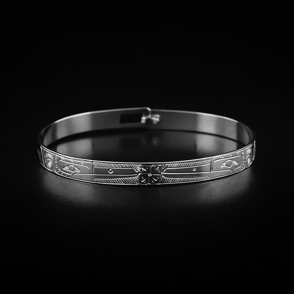 This Hummingbird bracelet is made from sterling silver and has a thin band with a clasp in the back. There are depictions of the Hummingbird with flowers carved into the surface of the band.