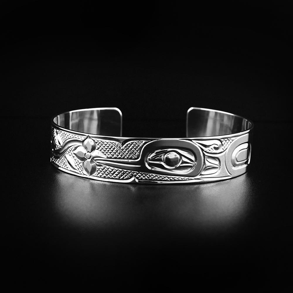 This Hummingbird bracelet is made from sterling silver and has a single band with a gap in the back. There is a depiction of the Hummingbird among flowers carved into the surface of the band.