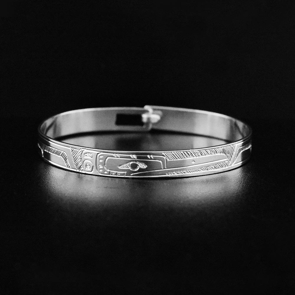 This babys silver bracelet is made from sterling silver and has a thin band with a depiction of the Hummingbird carved into the surface of the band.