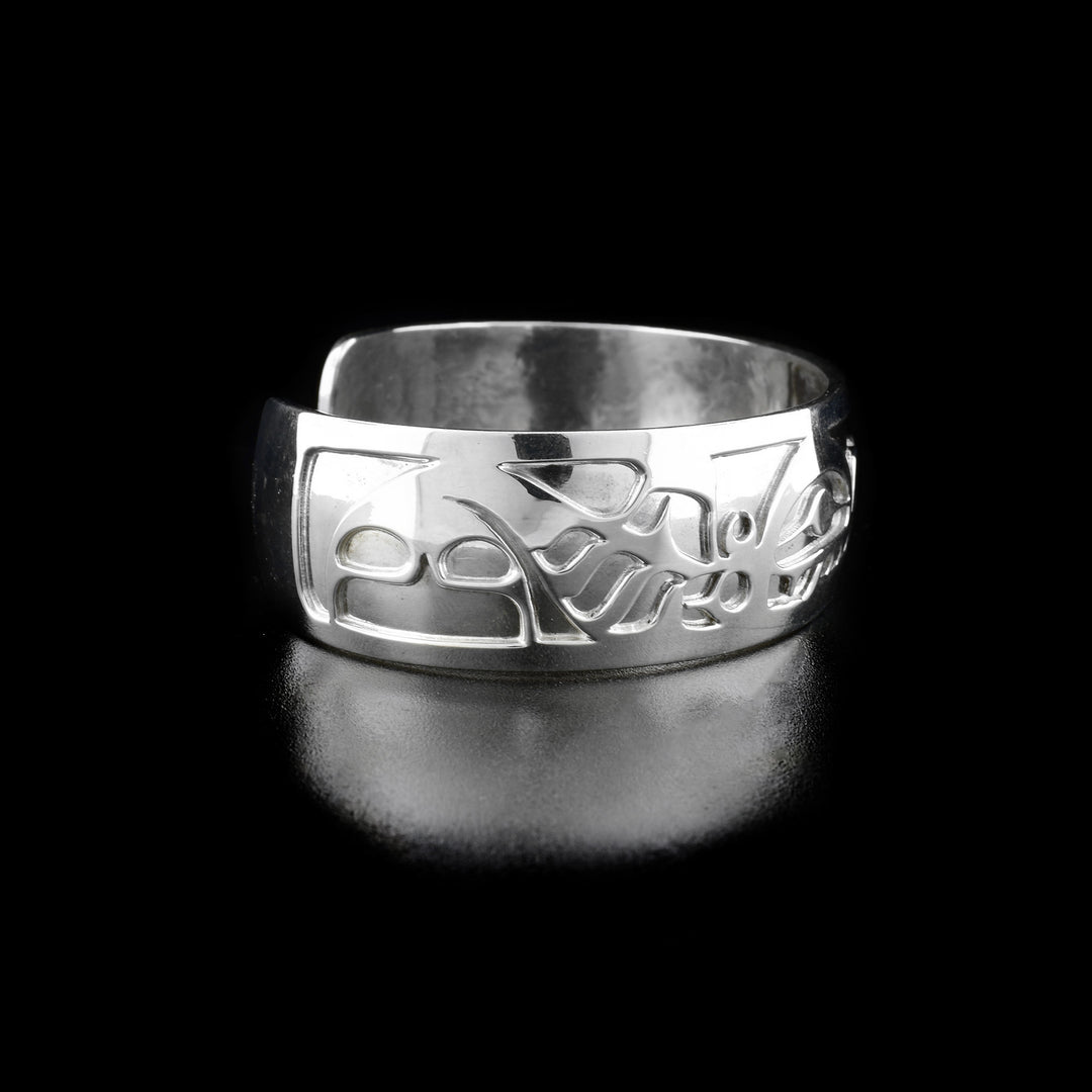 Left angle photo of the bracelet shows carved designs representing the first orca's body, fins, and tail.